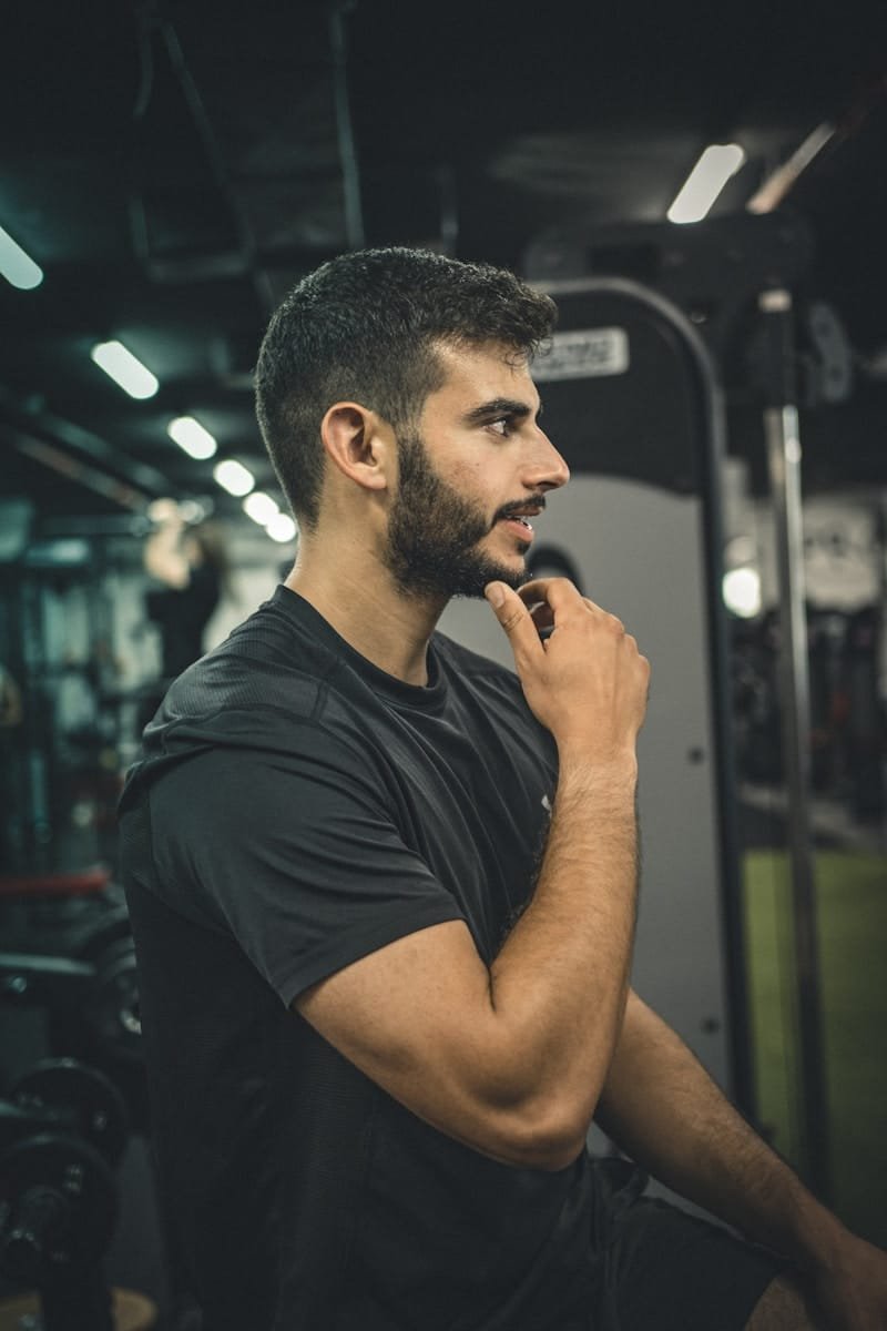 a man in a black shirt standing in a gym